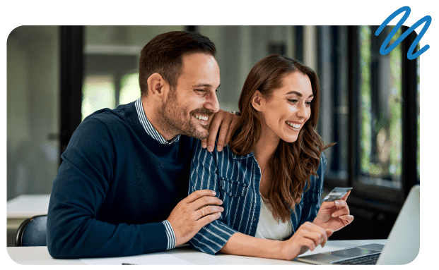 Woman paying with credit card on laptop while man sits behind her holding onto her.