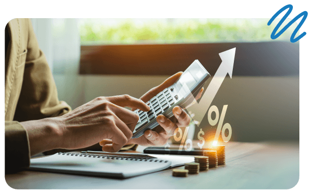 Person sitting at desk with paper, pen and coins stacked in front of them while punching in numbers on calculator.