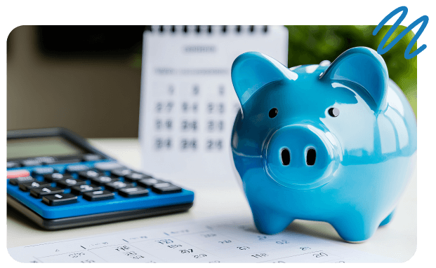 Blue piggy bank sitting on desk surface beside calculator and calednar in background.