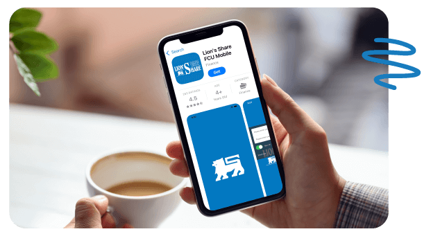 Person sitting at table holding coffee cup in one hand and phone in the other.