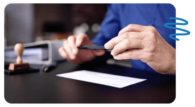 Person using cell phone to take picture of check on desk.