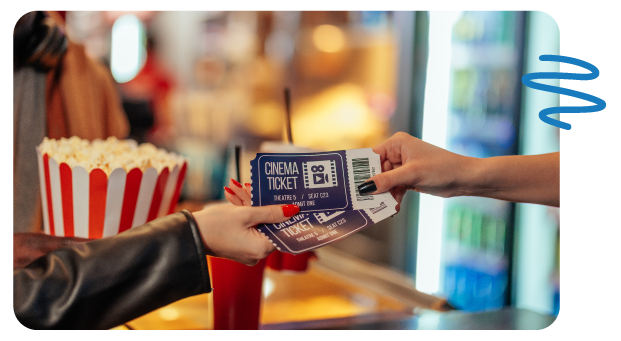 One woman exchanging movie tickets with another with drinks and popcorn positioned in background.