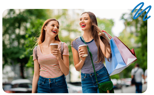 Two young women holding coffee and shopping bags.
