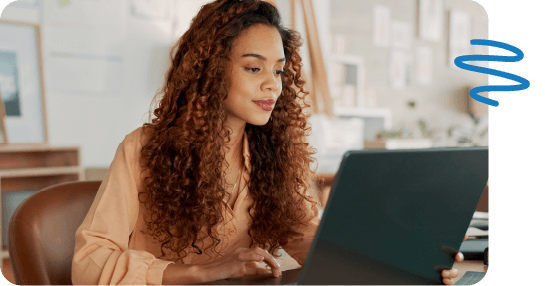 Woman sitting at desk in leather chair using laptop