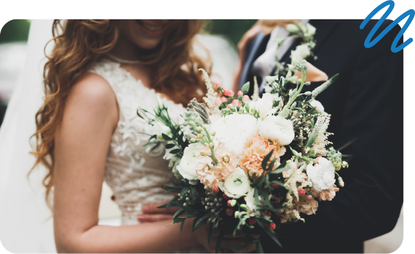 Man and woman dressed for wedding day holding bouquet of flowers.