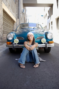 Portrait of a Young Woman With Dreadlocks Leaning Against a Classic Blue Car